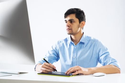 Young graphic designer sitting at desk and working