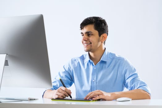 Young graphic designer sitting at desk and working