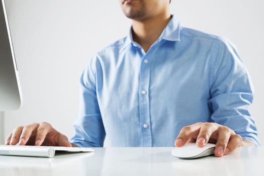 Young man sitting at desk and typing on keyboard