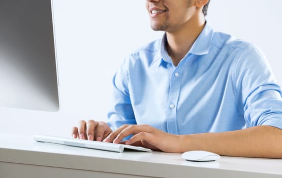 Young man sitting at desk and typing on keyboard