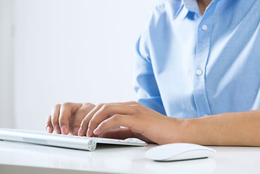 Young man sitting at desk and typing on keyboard