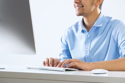 Young man sitting at desk and typing on keyboard