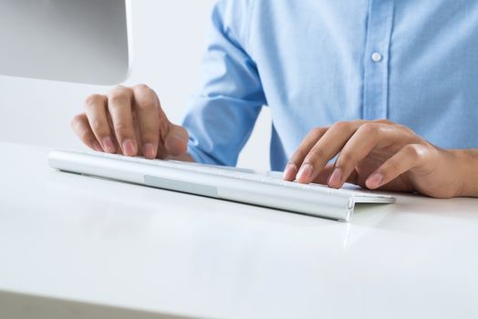 Young man sitting at desk and typing on keyboard