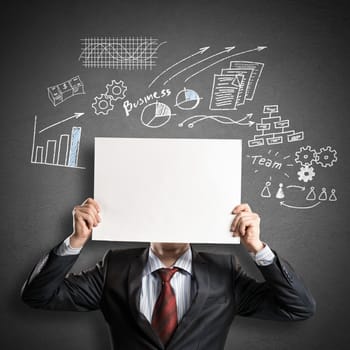 Businessman hiding his face behind sheet of paper