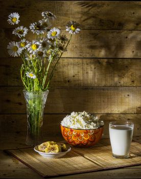Still life with milk, curd, honey comb and a bouquet of daisies, summer breakfast