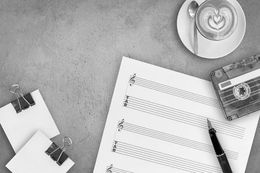 Sheet music, fountain pen, tape cassette and coffee latte on wooden table, top view picture