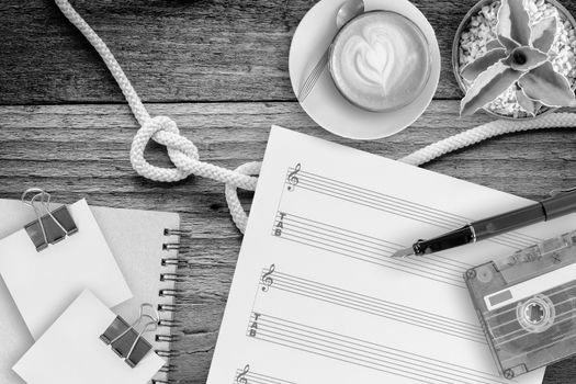Sheet music, cactus, fountain pen, tape cassette and coffee latte on vintage wooden table