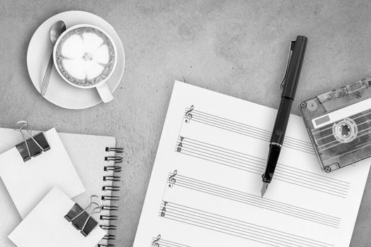 Sheet music, fountain pen, tape cassette and coffee latte on wooden table, top view picture