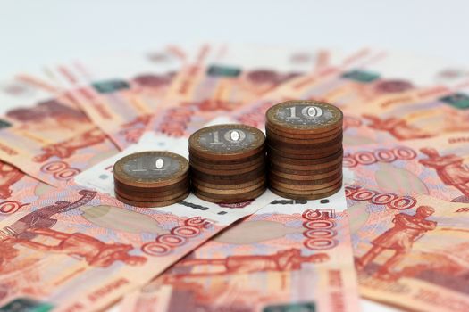 A stack of Russian commemorative ten-coins on background five-thousandth banknotes