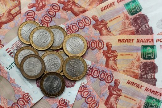 Russian money of five thousands denominations and commemorative coins lie on the table mixed