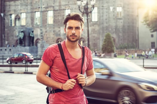 One handsome young man in urban setting in European city, Turin in Italy. Looking at camera, walking