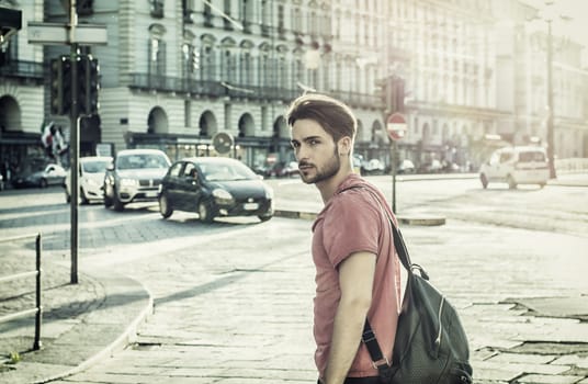 One handsome young man in urban setting in European city, Turin in Italy. Looking at camera, walking