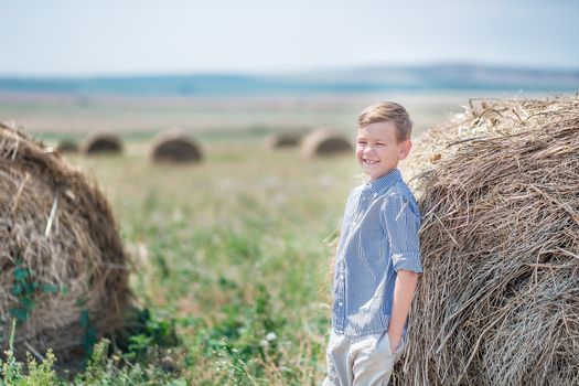 Attractive boy sitting on a haystack and smiling.