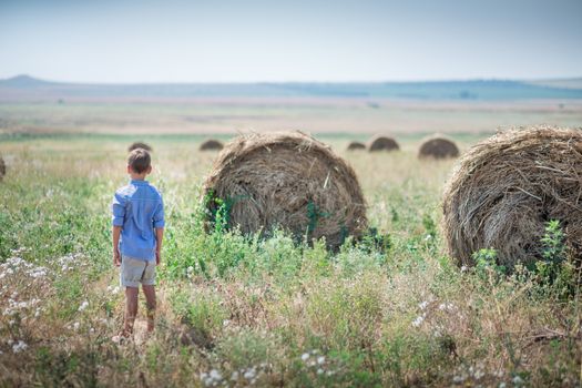 Attractive boy sitting on a haystack and smiling.