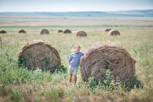 Attractive boy sitting on a haystack and smiling.