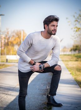 One handsome young man in urban setting in European city park, standing