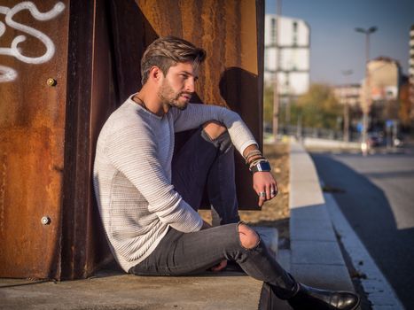 One handsome man in urban setting in European city, sitting