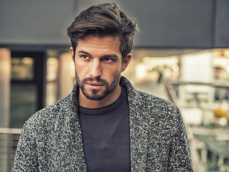 One handsome young man in urban setting in European city, standing