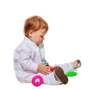 Baby boy playing with colorful pyramid toy isolated on white