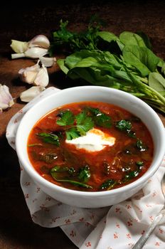 Vegetable bowl, tomato soup with spinach and sour cream. Vertical shot.