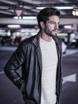 Handsome muscular man in casual clothing on background of parking.