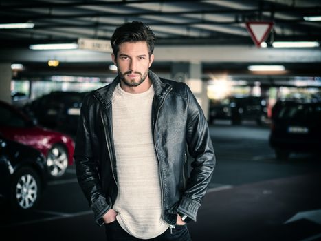 Handsome muscular man in casual clothing on background of parking.