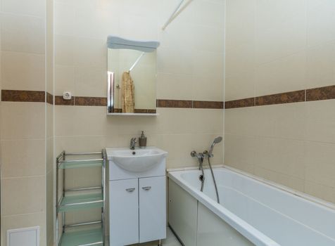 Small beige tile bathroom with bath tube and sink