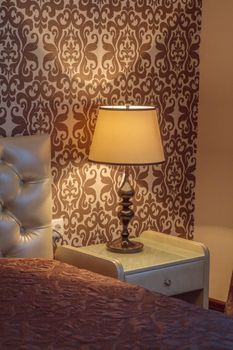 Warm cozy lamp near bed on nightstand