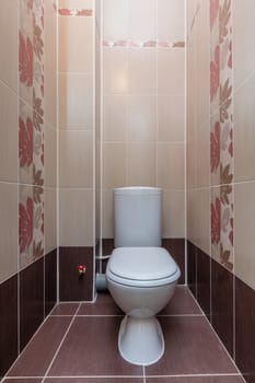 Toilet bowl in the toilet room. Restroom with brown tile decoration