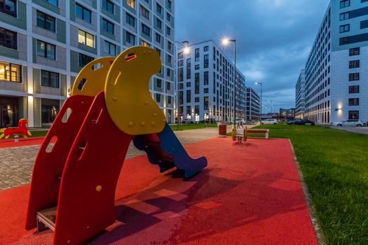 Colorful playground equipment for children in apartment building yard in evening