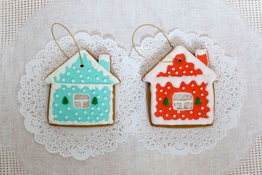 Two gingerbread cookies in the shape of the small cottage on a white napkin background. Top view, flat lay, copy space. Curly Christmas gingerbread home cooking