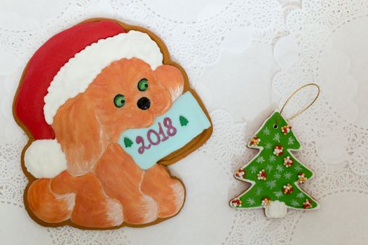 Two gingerbread cookies in the shape of Christmas tree and dog on a white napkin background. Top view, flat lay, copy space. Curly Christmas gingerbread home cooking. Happy new year 2018