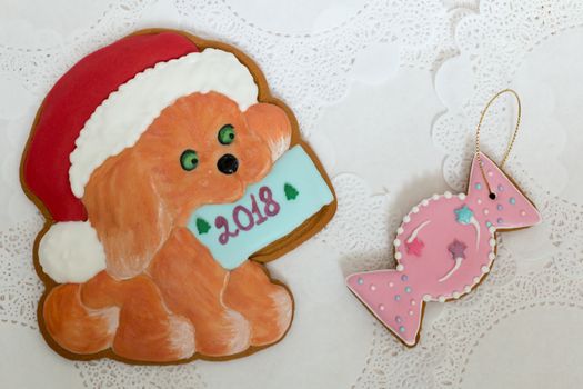 Two gingerbread cookies in the shape of Christmas dog and candy on a white napkin background. Top view, flat lay, copy space. Curly Christmas gingerbread home cooking. Happy new year 2018