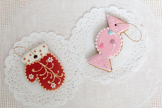 Two gingerbread cookies in the shape of candy and red mitten on a white napkin background. Top view, flat lay, copy space. Curly Christmas gingerbread home cooking