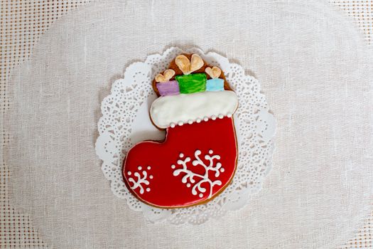 Christmas gingerbread sock with gifts on a background of napkin. Christmas stocking gingerbread cookie, decorated with Icing. New year concept