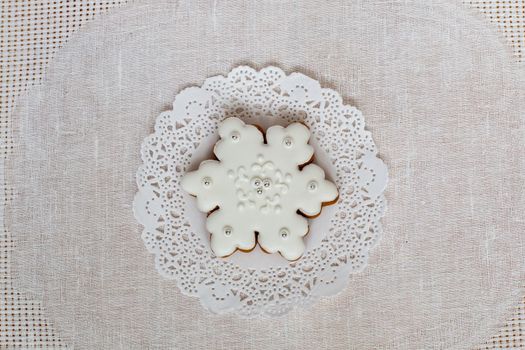 Christmas gingerbread snowflake on a background of napkin. Christmas toy gingerbread cookie, decorated with Icing. New year concept