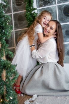 Smiling mother and daughter in snowy winter studio hugging