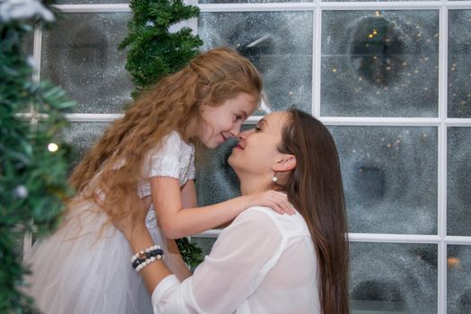 Mother and daughter nose-to-nose hugging in winter studio
