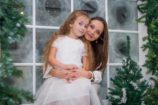Smiling mother and daughter in snowy winter studio