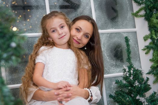 Smiling mother and daughter in snowy winter studio