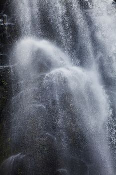 Mountain waterfall falling on the rocks. Dark background.