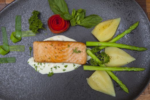 Atlantic salmon with a rocket salad,Decorated with vegetables on a black plate.