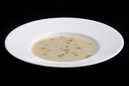 cream soup in a plate top view soup decorated with green onions
