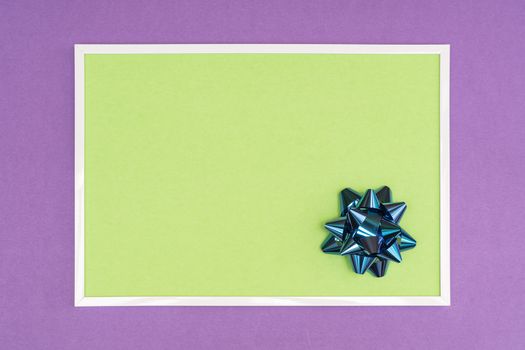 Christmas decorative bow in a white frame on a colored background
