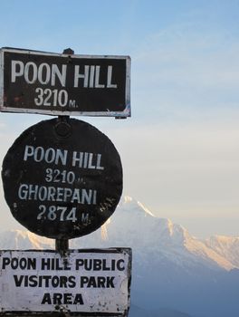Poon Hill visitor park sign with snowy mountains in the background on a cold winter morning.