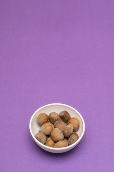 hazelnuts in a bowl on a colored background