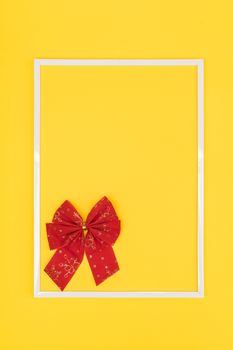 Christmas decorative red bow in a white frame on a colored background