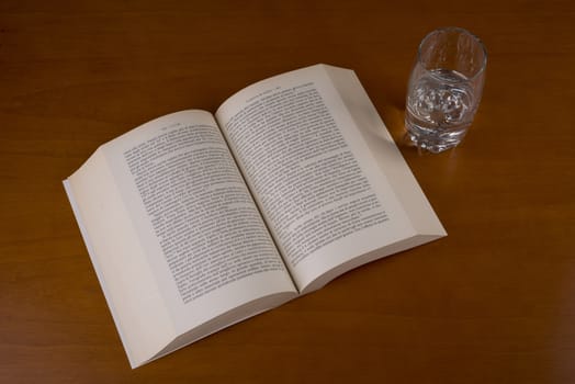 an open book with a glass of water alongside