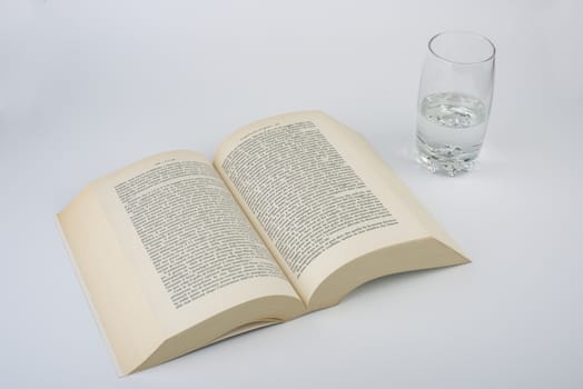 an open book with a glass of water alongside