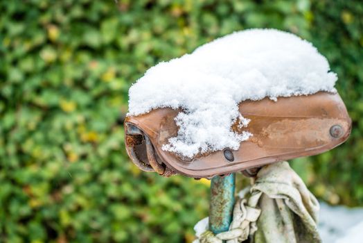 Old leather saddle covered with snow in the winter